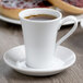 A Schonwald white porcelain espresso cup full of brown liquid on a saucer.