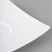 A close-up of a Schonwald white porcelain saucer with a curved edge.