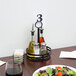 A table with a plate of salad and a number on it with a wrought iron condiment caddy holding salt and pepper shakers and a card holder.