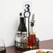 A black wrought iron condiment caddy on a table with food and wine.