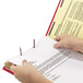A person's hands holding a legal document in a red Smead SafeSHIELD folder.