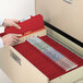 A person opening a file drawer with Smead red legal size folders inside.