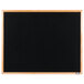 A black Aarco indoor message board with an oak wood frame.