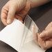 A person's hand holding a piece of paper being inserted into a clear poly pocket.