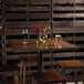 A Lancaster Table & Seating solid wood live edge table top with a glass of beer and flowers on it.