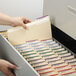 A hand opening a file drawer with Smead Manila file folders inside.