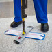 A person using a Rubbermaid HYGEN Pulse Spray Mop to clean a floor.