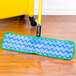 A green Rubbermaid wet mop pad attached to a mop on a wood floor.