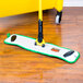 A Rubbermaid green microfiber wet mop pad on a wooden floor.