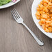 A Libbey stainless steel dinner fork on a plate of pasta with sauce.