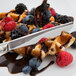 A waffle with chocolate sauce and berries on it with a Libbey Baguette stainless steel dinner knife.