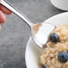 A Libbey Cortland stainless steel serving spoon in a bowl of oatmeal with blueberries.