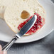 A Libbey stainless steel bread and butter knife on a plate with a bagel and jam.