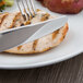 A Libbey stainless steel dinner knife and fork on a piece of meat.