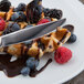 A Libbey Cortland stainless steel utility knife cutting a waffle with berries and chocolate sauce.