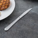 A Libbey Cortland steak knife on a table next to a plate of food.