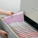 A person opening a file cabinet with a stack of Smead Lavender File Folders