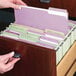 A person holding a lavender Smead file folder with several files inside.