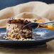 A World Tableware Columbus stainless steel dessert spoon with chocolate on it, on a plate of chocolate ice cream.