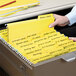 A person holding a Smead yellow FasTab file folder.