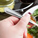 A hand holding a Libbey stainless steel salad fork over a plate of food.