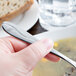 A person holding a Libbey stainless steel bouillon spoon over a bowl of soup.