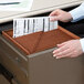A person putting a Smead TUFF file into a file drawer.