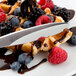 A Libbey stainless steel knife cutting a waffle with berries and chocolate syrup.