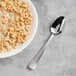 A bowl of cereal with milk and a Libbey stainless steel teaspoon.