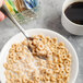 A Libbey stainless steel teaspoon holding cereal over a bowl.