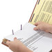 A person's hand holding a Smead legal size file folder containing a proposal document.