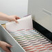 A hand opening a file drawer filled with several Smead file folders.
