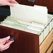 A person opening a file drawer with a Smead white file folder inside.