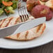A Libbey stainless steel dinner knife and fork on a plate of food.