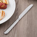 A Libbey stainless steel serrated dinner knife on a plate of food.