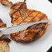 A Libbey stainless steel fluted handle steak knife cutting a piece of meat.