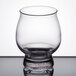 A close-up of a Libbey Kentucky Bourbon Tasting Glass with a small amount of liquid in it on a table.