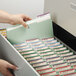 A hand opening a file drawer with a stack of Smead 100% Recycled Fastener Folders inside.