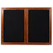 A wooden cabinet with a black board and wooden framed black glass doors.