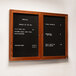 An Aarco cherry-framed bulletin board with black felt and two doors on a wall with a menu.