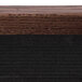 The walnut wood surface of an Aarco enclosed message board with black trim.