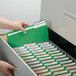 A hand opening a file drawer with Smead green file folders inside.