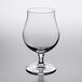 A clear Reserve by Libbey Belgian beer glass with a stem on a table.