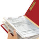 A hand holding a red Smead Heavy Weight Letter Size Classification Folder
