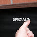 A person pointing to a black felt message board with a walnut frame.