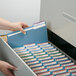 A hand opening a blue Smead file folder in a file cabinet.
