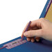 A person's hand holding a blue Smead SafeSHIELD classification folder with a pen.