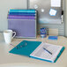 A blue Smead SuperTab file folder with papers and glasses on a desk.