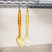 Two Cambro amber high heat perforated salad bar spoons hanging from a rack.