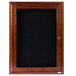An Aarco cherry wood cabinet door with a black felt message board inside.